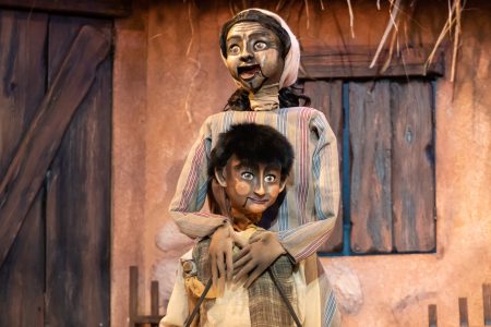 Two wooden puppets: A mother hugs her young son and sings.