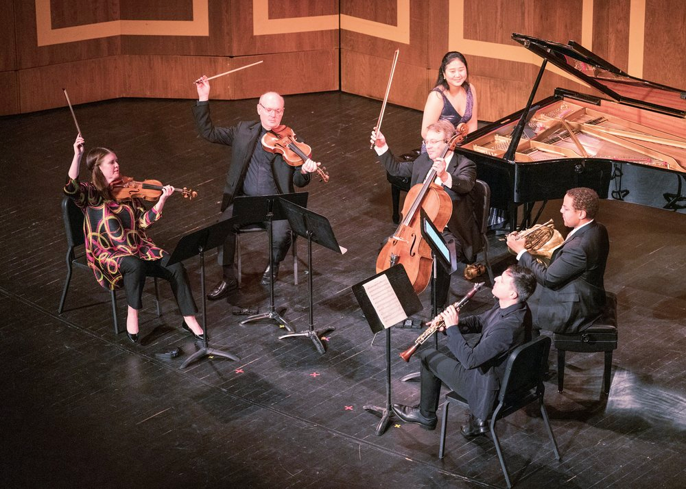 Six musicians on stage having just finished performing. 