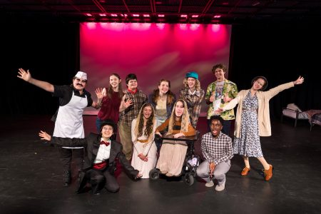 A group of young actors poses dramatically on a stage.