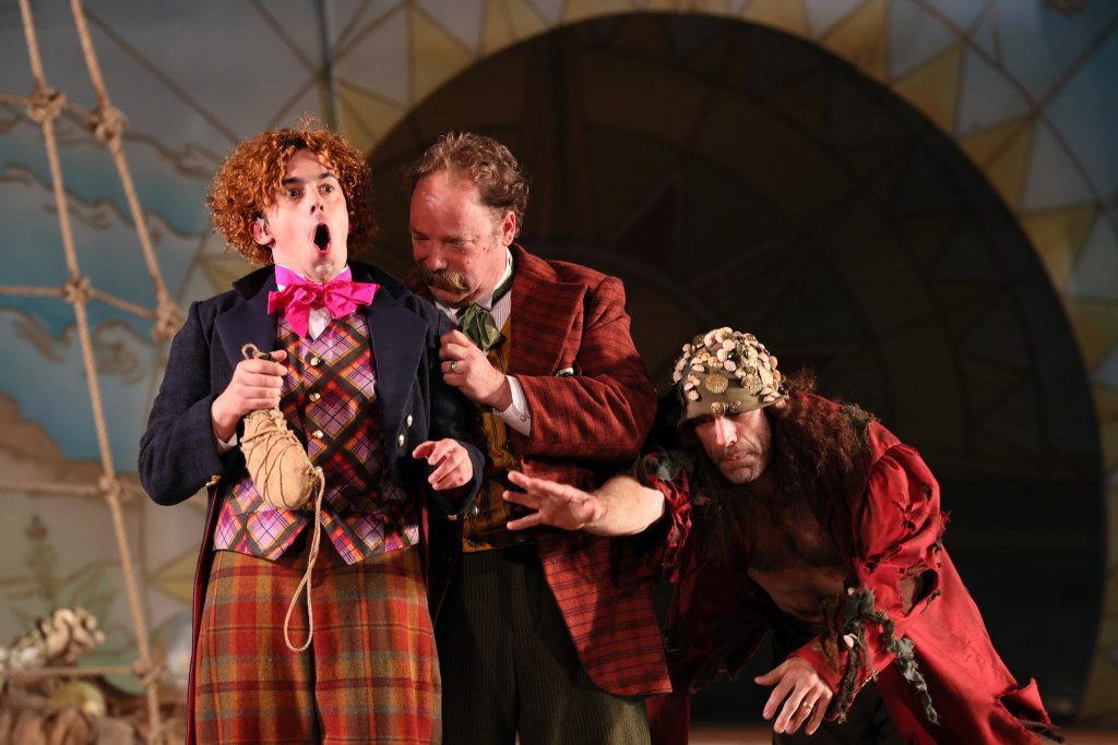 Three actors make exaggerated facial expressions in a scene from The Tempest.