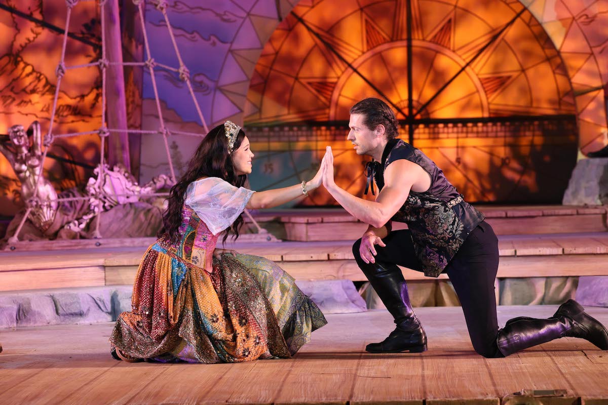 Miranda and Ferdinand touch palms lovingly in a scene from The Tempest.