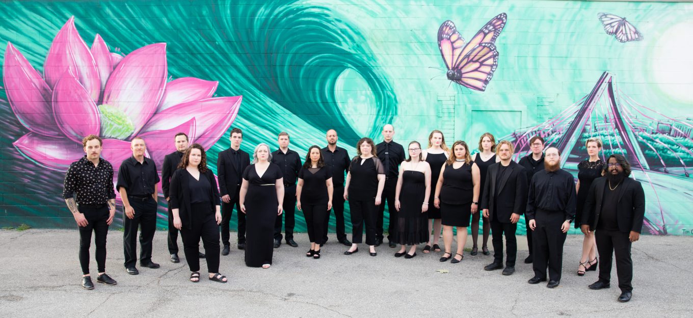 Members of KC VITAs dressed in black clothing stand in front of a teal mural with a pink flower and purple butterfly.