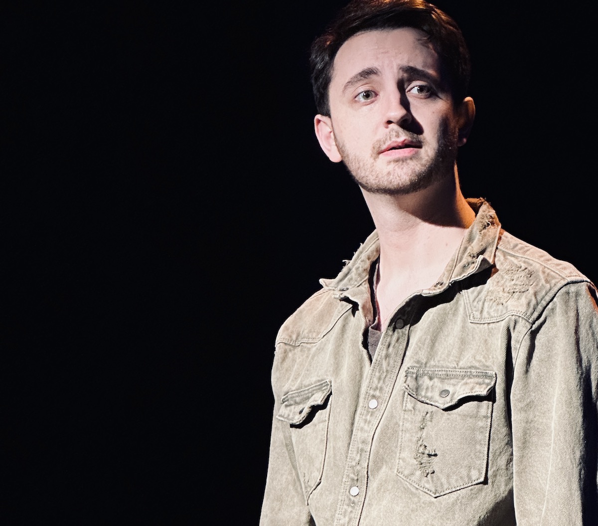 A young man looks wistfully off to the side.