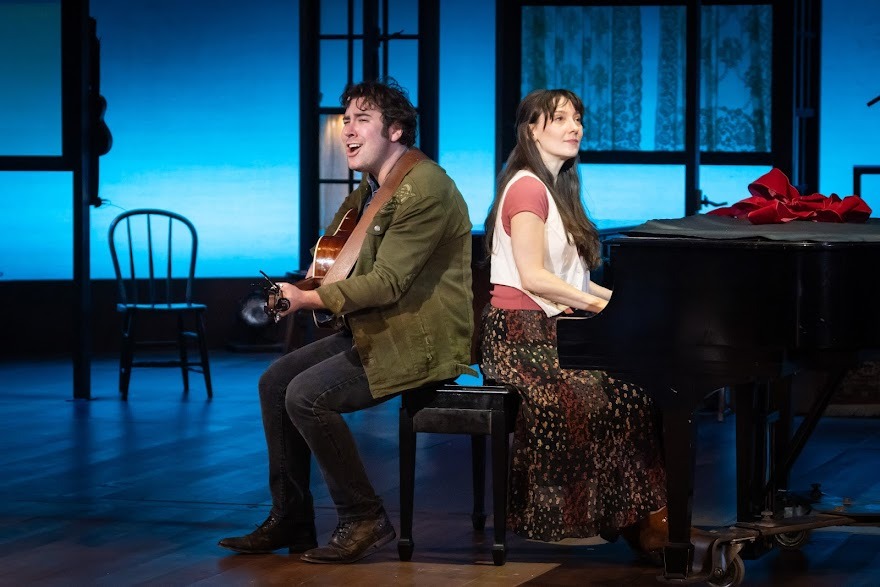 A woman sits playing a piano while a man wits with his back to hers, playing a guitar