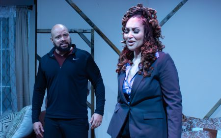 Two Black actors perform a dramatic scene onstage.