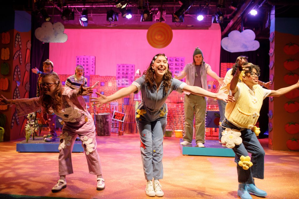 A group of young actors gesture with arms open.